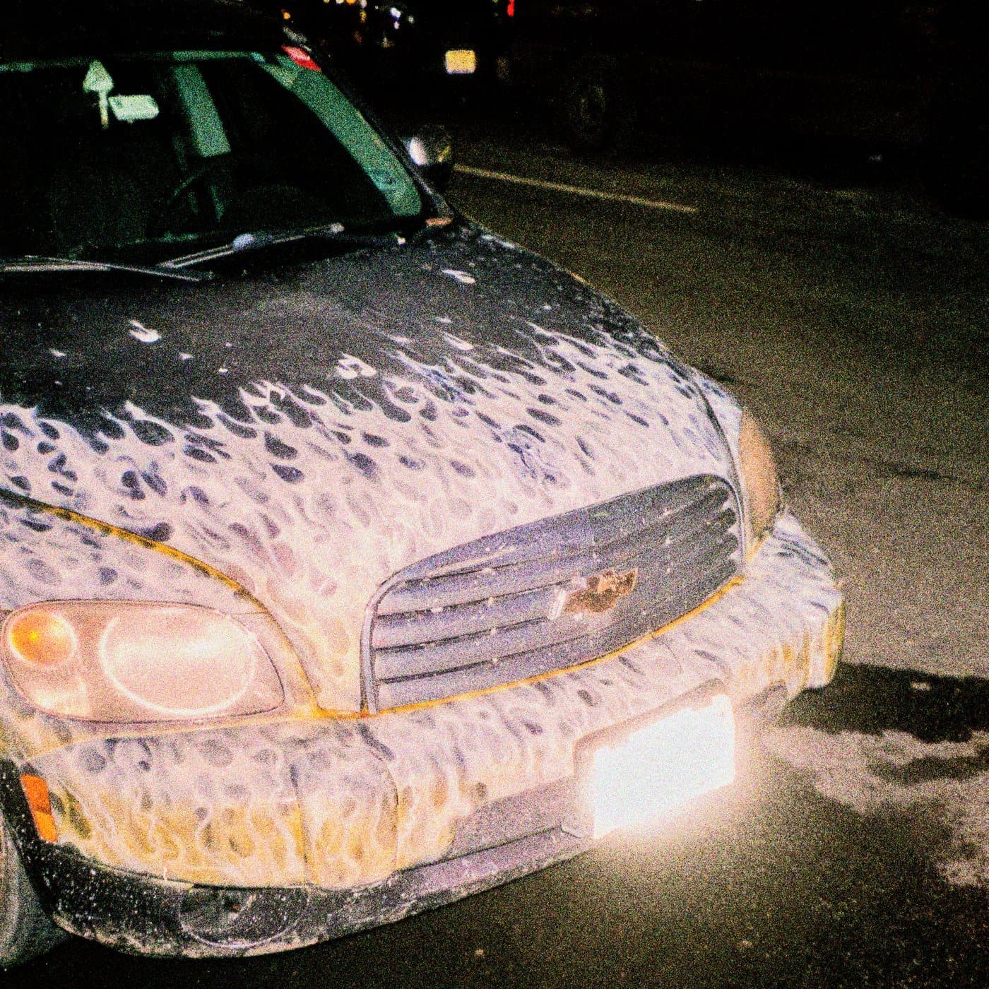 Reality cover: a flame-painted car lit by a camera flash at night